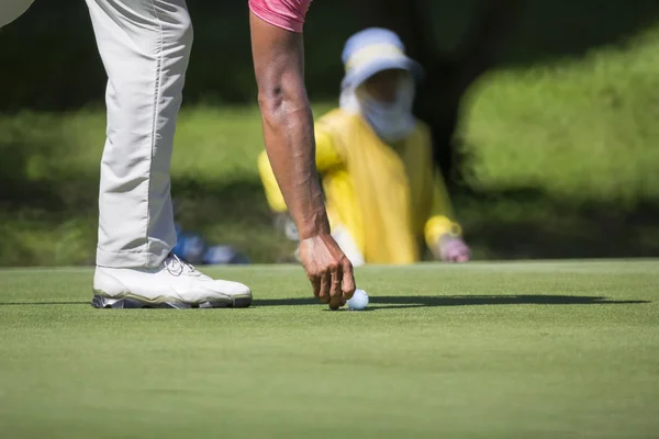 高尔夫球手标志着他在一座绿色的球位置 — 图库照片