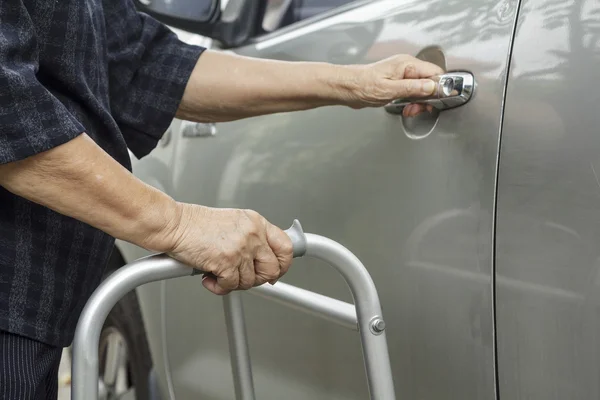 Senior vrouw met behulp van een walker op parkeerplaats — Stockfoto