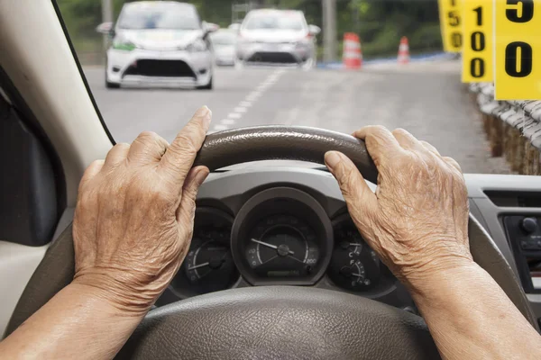 Äldre kvinna kör bil på väg. — Stockfoto
