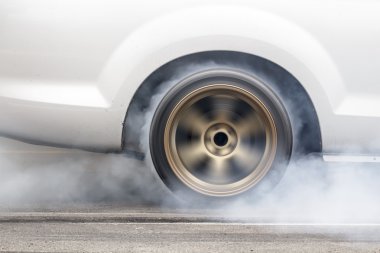 race car burns rubber off its tires in preparation for the race