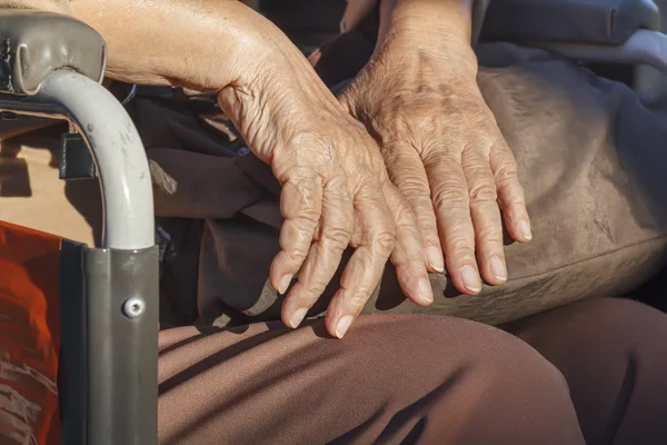 Elderly hands on a wheelchair. — Stock Photo, Image