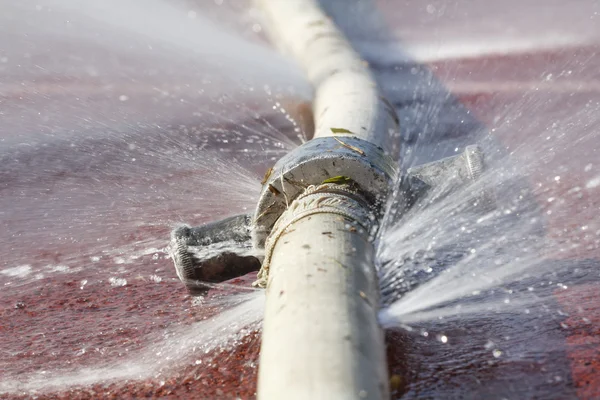 Desperdicio de agua: fugas de agua del orificio de una manguera —  Fotos de Stock