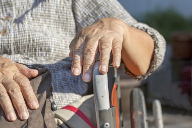 Yaşlı bir tekerlekli sandalye üzerinde eller.