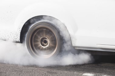 race car burns rubber off its tires in preparation for the race