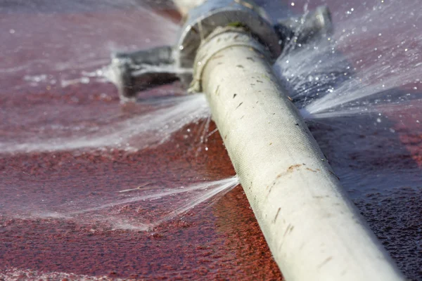 Verspilling van water - water lekken uit gat in een slang — Stockfoto