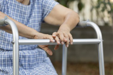 Walker ile arka bahçesinde oturan yaşlı.