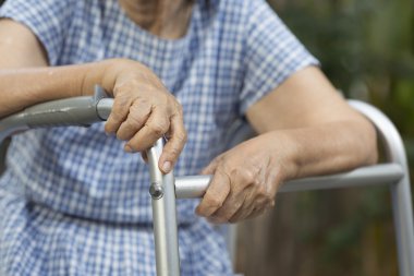 Walker ile arka bahçesinde oturan yaşlı.