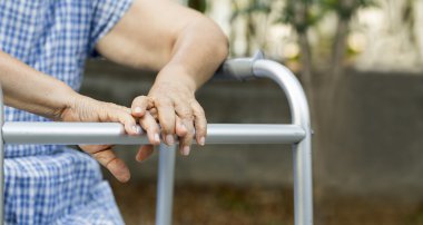 Walker ile arka bahçesinde oturan yaşlı.