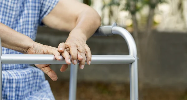 Walker ile arka bahçesinde oturan yaşlı. — Stok fotoğraf