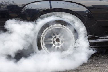 Drag racing car burns rubber off its tires clipart