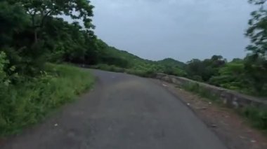 Dağ yolunda bisiklet sürmek. Önümüzde sabah yeşil bir orman ve dağ manzarası var..