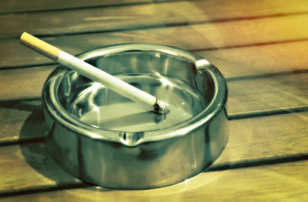 Cendrier en métal avec une cigarette sur une table — Photo