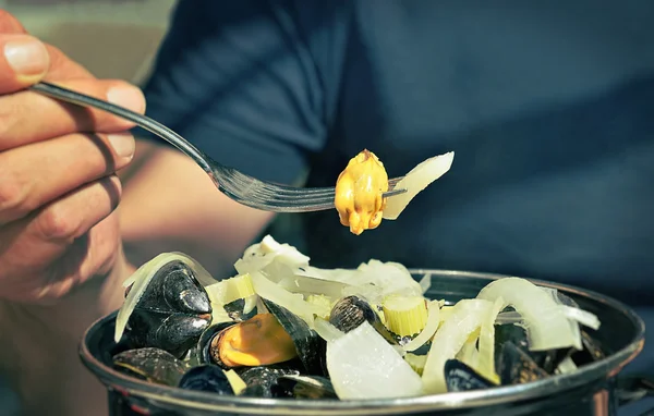 Hand of a person holding a fork with a mussel — Stock Photo, Image