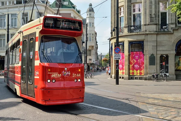 Czerwony tramwaj porusza się przy ulicy w zabytkowym centrum Hagi. — Zdjęcie stockowe