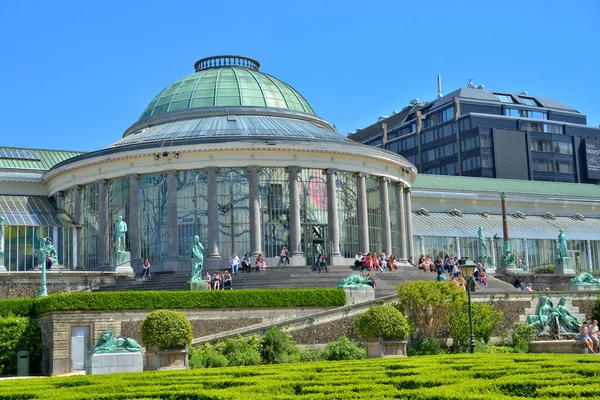 People sit around exhibition building in Botanique garden during lunch time