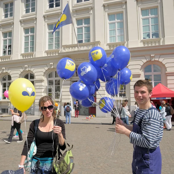 Deelnemers distribueren geschenken tijdens de jaarlijkse dag van Iris - Fete de l'Iris op 5 mei 2013 in Brussel. — Stockfoto