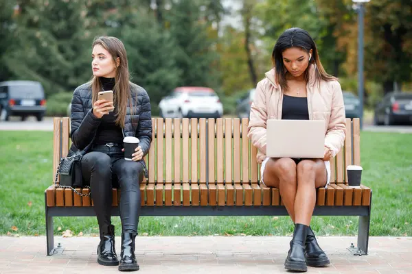 Two different women sitting on the bench in park — Stock Photo, Image