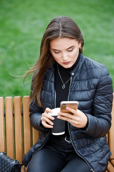 Young beautiful woman using smartphone in the park — Stock Photo, Image