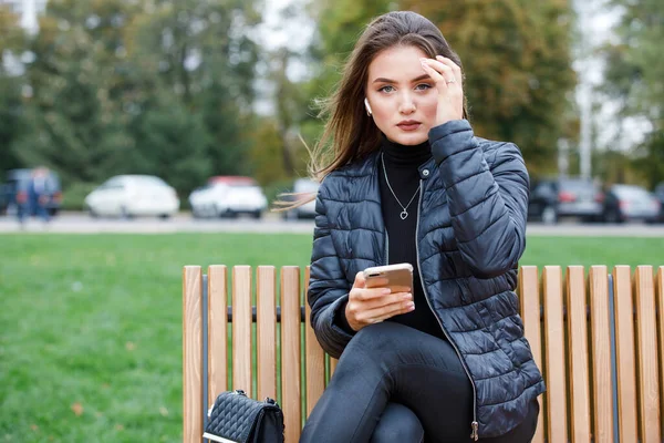 Jonge mooie vrouw met smartphone in het park — Stockfoto