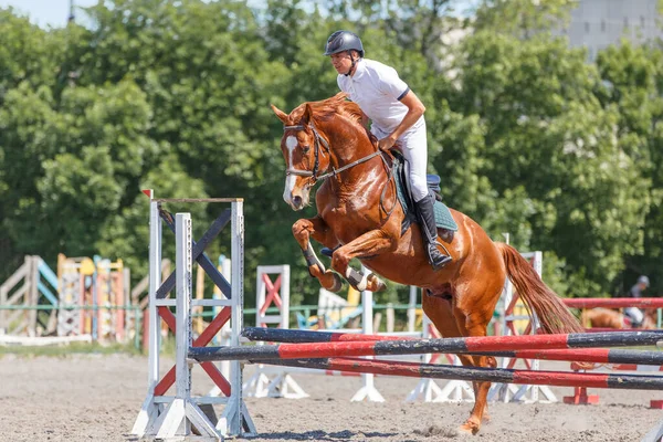 Jeune homme cavalier sautant par-dessus la barrière — Photo