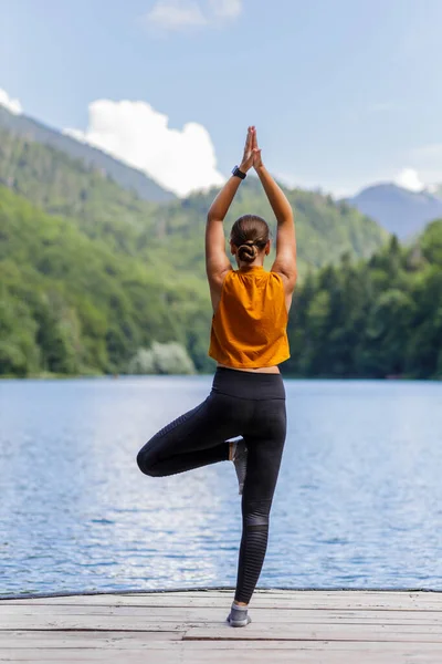 Junge Frau beim morgendlichen Yoga in der Nähe des Sees — Stockfoto