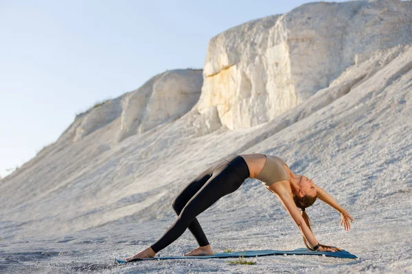 Mujer joven practicando yoga en acantilados blancos por la mañana. cosa salvaje yoga pose contra puesta de sol — Foto de Stock