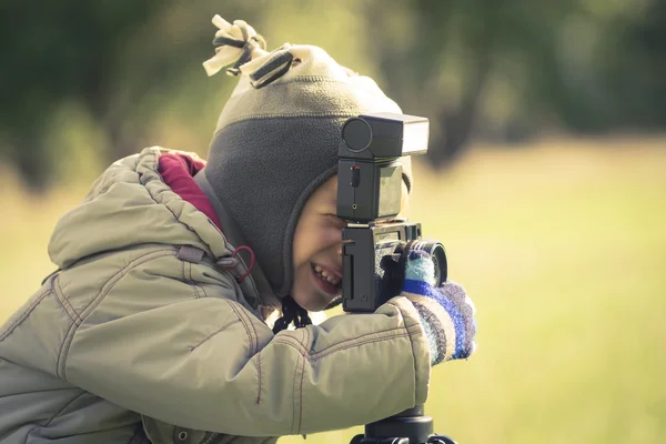 Söt liten pojke skytte en fotografering i höst park — Stockfoto