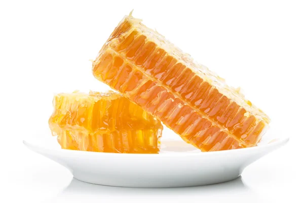 Разрезанный свежий медовый гребешок, уложенный на тарелке, изолированной на белом фоне — стоковое фото