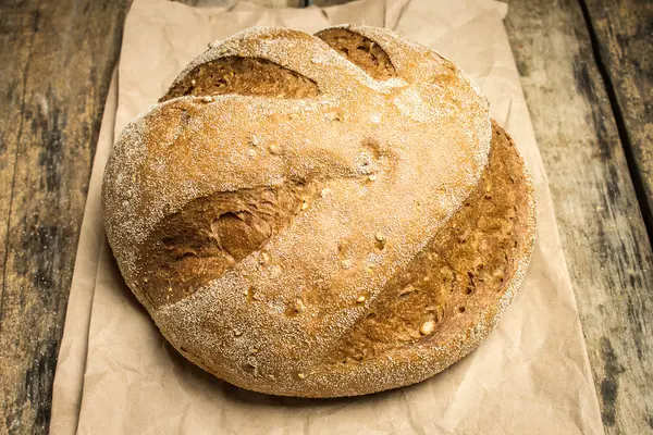 Wheat bread with paper bag on wooden table — Stock Photo, Image