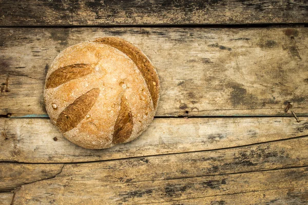 Loaf of whole wheat grains bread on wood background — Stock Photo, Image