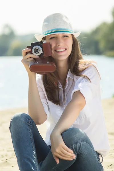 Yong hipster flicka skytte med gamla kameran på stranden. — Stockfoto