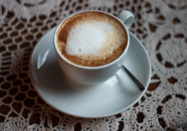 Cup of cappuccino served on table with lace tablecloth — Stock Photo, Image