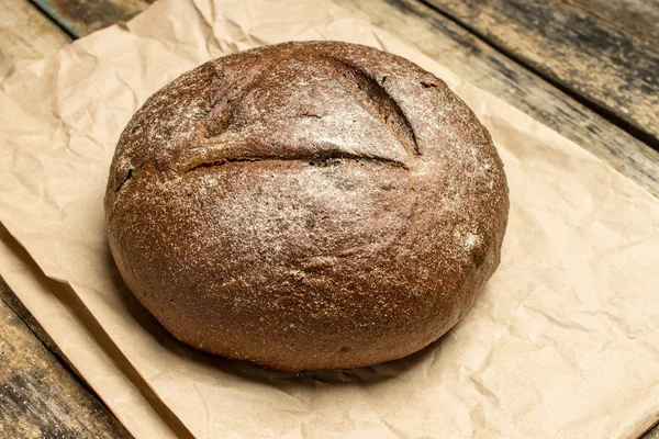 Pane appena sfornato su sacchetto di carta al tavolo di legno — Foto Stock