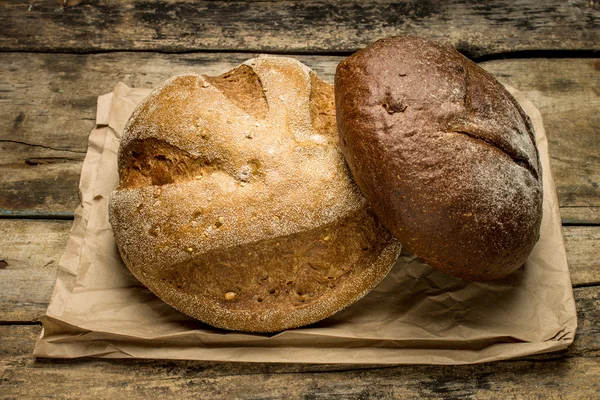 Loafs chleba na papierową torbę na drewniane tła — Zdjęcie stockowe