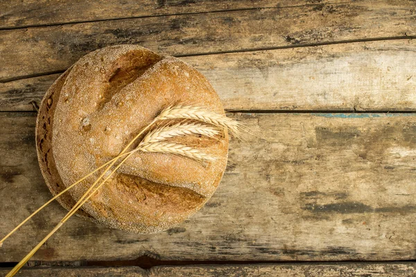 Pane integrale con spighe su fondo legno — Foto Stock