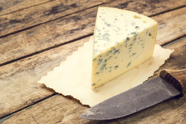 Blue cheese on old paper with rural knife — Stock Photo, Image