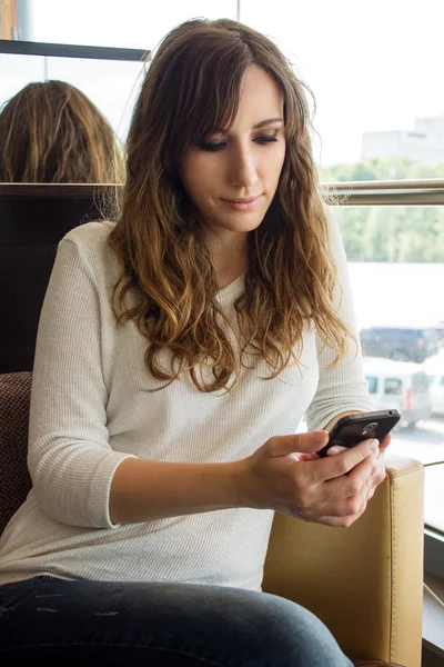 Young woman waiting in restaurant using her smartphone — Stock Photo, Image