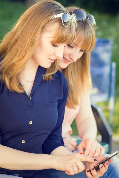 Pretty young women using smartphone in summer park — Stock Photo, Image