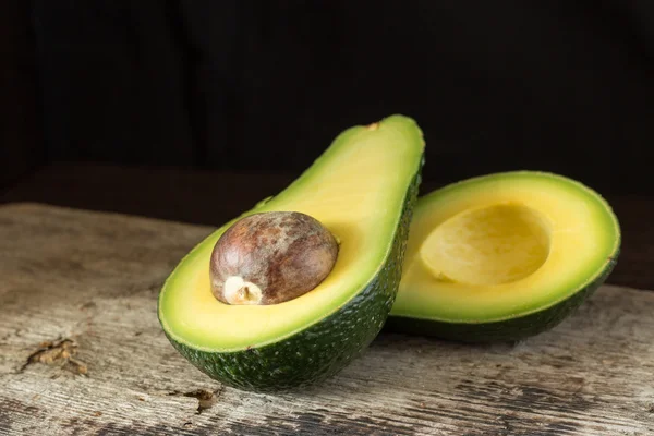 Avocat coupé en deux sur une vieille planche en bois — Photo