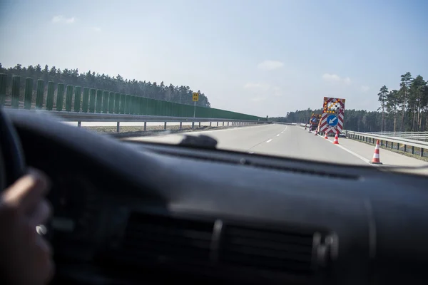 Conduire une voiture sur l'autoroute avec un panneau de warnig sur le raod — Photo