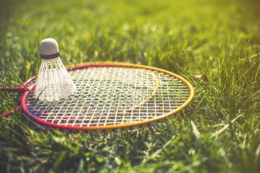 Yeşil çimenlerin üzerinde raketle ve badminton raket