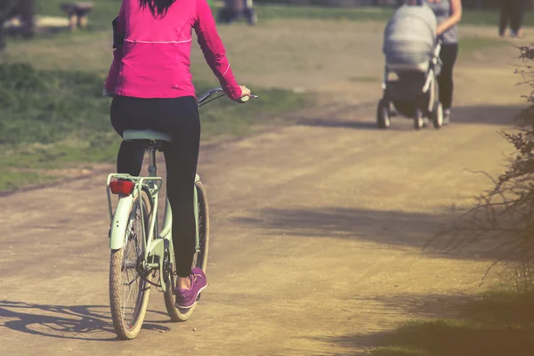 Μια νεαρή γυναίκα ποδηλασία στο ηλιοβασίλεμα στο πάρκο — Φωτογραφία Αρχείου