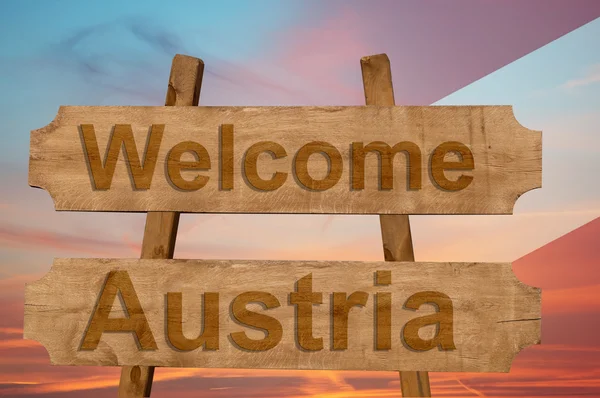 Välkommen till Österrike sjunga på trä bakgrund med blandning flagga — Stockfoto