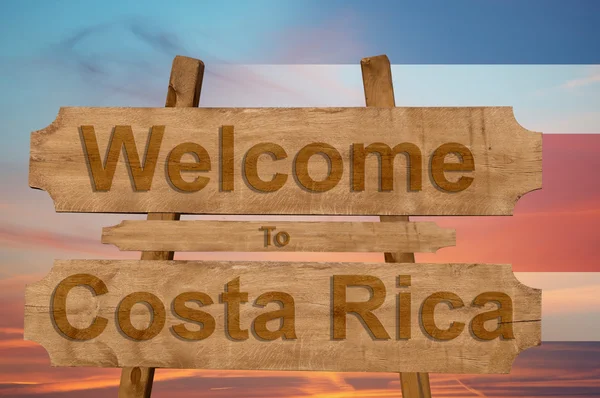 Ласкаво просимо в Коста-Ріці співати на деревини фон з накладання Національний прапор — стокове фото