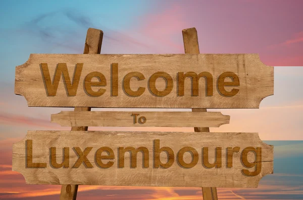 Welkom bij Luxemburg teken op hout achtergrond met het mengen van de nationale vlag — Stockfoto