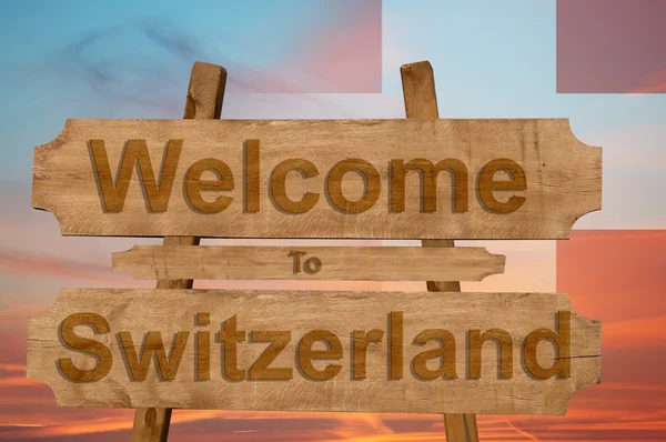 Ласкаво просимо до Швейцарії знак на деревини фон з накладання Національний прапор — стокове фото