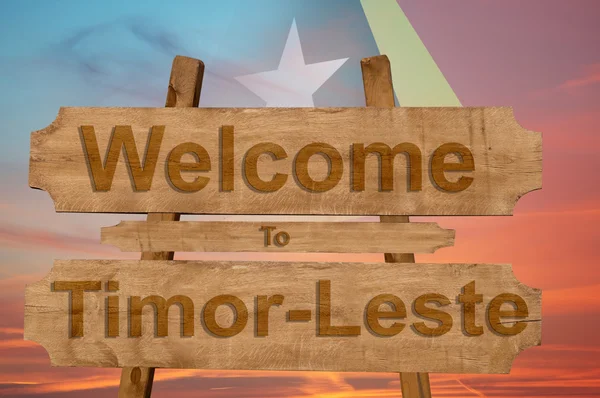 Welkom bij Oost Timor zingen op hout achtergrond met het mengen van de nationale vlag — Stockfoto