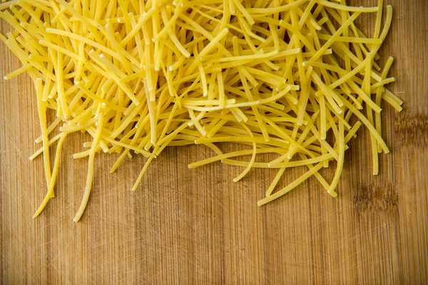 Cerrar en Pequeños fideos de pasta seca sobre fondo de madera — Foto de Stock