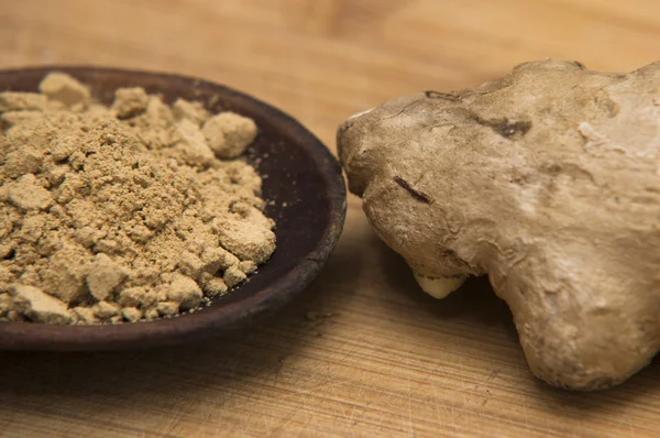 Close up on fresh ginger and powder on wood — Stock Photo, Image