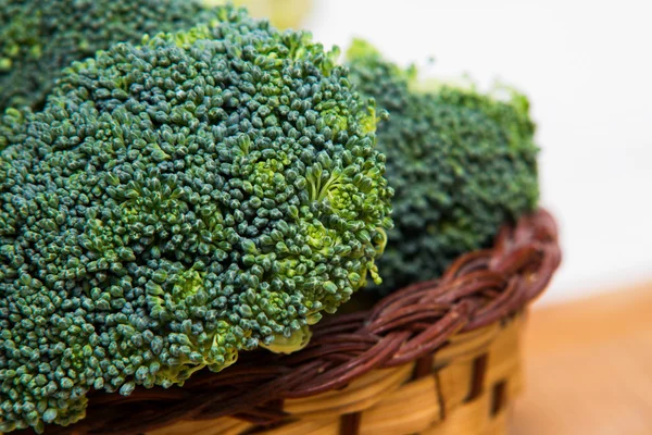 Close up on Fresh broccoli solated in basket on wood and white background — Stock Photo, Image